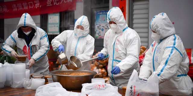 In this photo released by China's Xinhua News Agency, volunteers wearing protective suits package meals for people under lockdown in Xi'an in China's Shaanxi Province, Tuesday, Jan. 4, 2022.