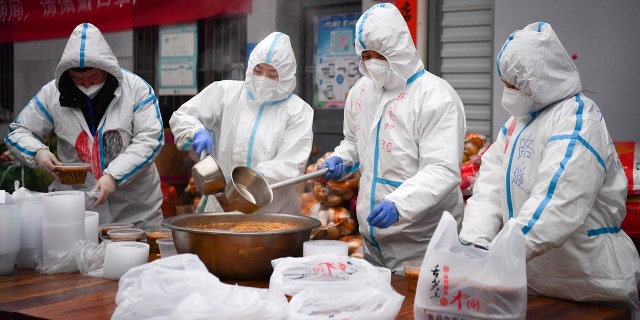 In this photo released by China's Xinhua News Agency, volunteers wearing protective suits package meals for people under lockdown in Xi'an in China's Shaanxi Province, Tuesday, Jan. 4, 2022.