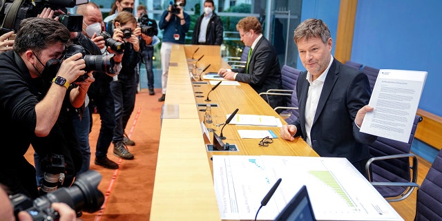 German Economy and Climate Minister Robert Habeck shows a report named "Opening balance climate policy" after he arrives for a news conference about the German government climate policy in Berlin, Germany, Tuesday, Jan. 11, 2022.Â