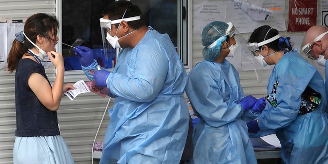 Health workers attend at a COVID-19 testing site in Brisbane, Australia, Friday, Jan. 7, 2022.