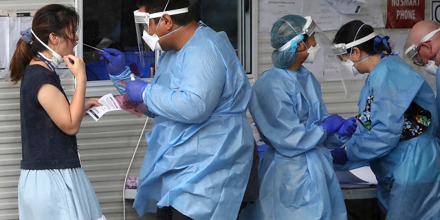 Health workers attend at a COVID-19 testing site in Brisbane, Australia, Friday, Jan. 7, 2022.