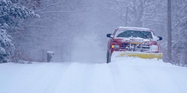 A truck removes snow from an unplowed road, Friday in East Derry, N.H.