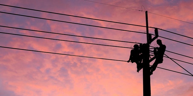 Electrician worker climbing electric power pole to repair the damaged power cable line problems after the storm. 