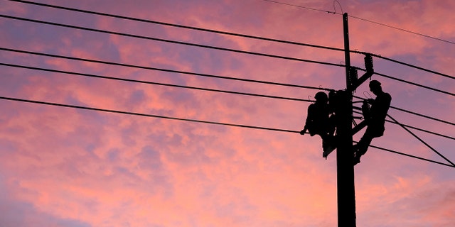 Electrician worker climbing electric power pole to repair the damaged power cable line problems after the storm. 