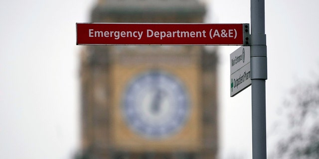 An Emergency Department sign at St Thomas' Hospital is backdropped by the Elizabeth Tower of the Houses of Parliament, known as Big Ben, 在伦敦, 星期四, 一月. 6, 2022.