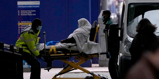 A patient is pushed on a trolley outside the Royal London Hospital in the Whitechapel area of east London, Thursday, Jan. 6, 2022. 
