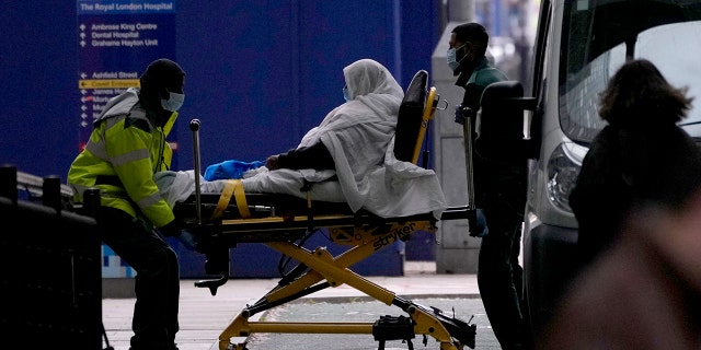 A patient is pushed on a trolley outside the Royal London Hospital in the Whitechapel area of east London, Thursday, Jan. 6, 2022.
