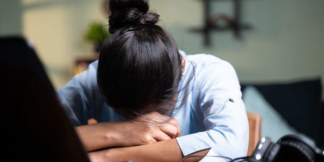 Una donna d'affari dorme spegnendo il suo laptop mentre lavora, il nuovo concetto normale di affaticamento, o lavorando a casa a tarda notte durante la pandemia di COVID-19.