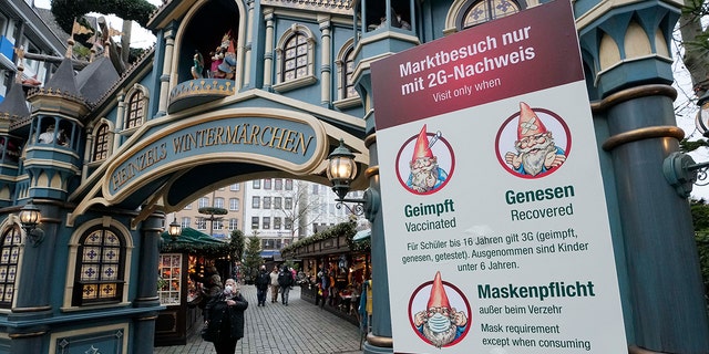 Un panneau sur un marché d'hiver à Cologne, en Allemagne, exige un masque obligatoire et la règle 2G, ce qui signifie que seuls les clients vaccinés ou récupérés sont autorisés à entrer, vendredi 7 janvier 2022. 