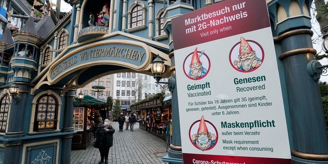 Un panneau sur un marché d'hiver à Cologne, en Allemagne, exige un masque obligatoire et la règle 2G, ce qui signifie que seuls les clients vaccinés ou récupérés sont autorisés à entrer, vendredi 7 janvier 2022. 