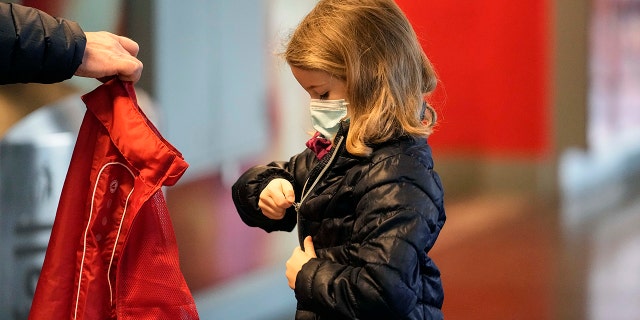 Six-year old Lotte puts on her jacket after she received her second coronavirus vaccination against the COVID-19 disease at the Laxness-Arena in Cologne, Germany, Friday, Jan. 7, 2022 where all participating children were rewarded for their vaccination.