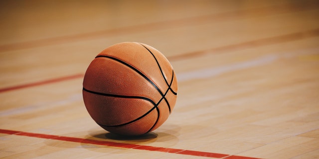 Classic Basketball on Wooden Court Floor Close Up with Blurred Arena in Background. Orange Ball on a Hardwood Basketball Court