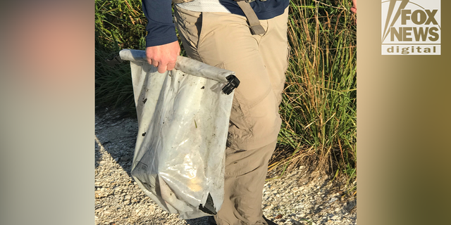 A police officer carries the dry bag that Chris and Roberta Laundrie found in the Myakkahatchee Creek Environmental Park Wednesday, Oct. 20, 2021.