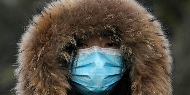 A woman wearing a mask to curb the spread of the coronavirus walks along a street in Beijing, China, Tuesday, Jan. 4, 2022