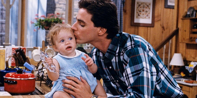 Bob Saget kisses one of the Olsen twin's heads on the set of ‘Full House’.