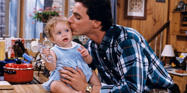 Bob Saget kisses one of the Olsen twin's heads on the set of ‘Full House’.