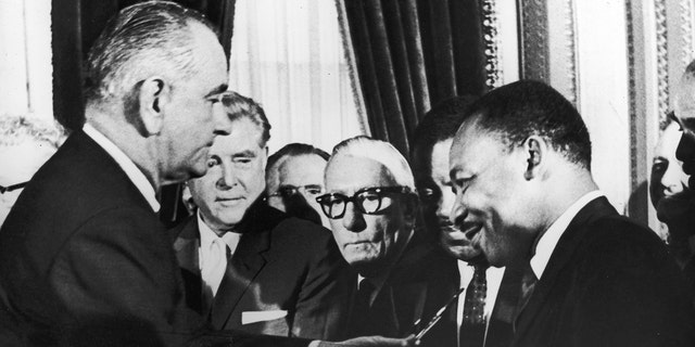 US President Lyndon B Johnson hands a pen to civil rights leader Reverend Martin Luther King Jr during the signing of the voting rights act Washington DC, Augustus 6, 1965. (Photo by Washington Bureau/Getty Images)