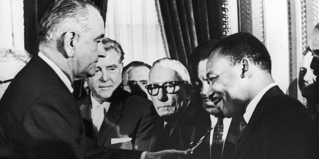 US President Lyndon B Johnson hands a pen to civil rights leader Reverend Martin Luther King Jr during the signing of the voting rights act Washington DC, August 6, 1965. (Photo by Washington Bureau/Getty Images)