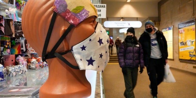 People walk past face masks displayed for sale in St. Petersburg, Russia, Monday, Jan. 24, 2022. (AP Photo/Dmitri Lovetsky)