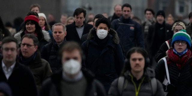 Workers walk over London Bridge towards the City of London financial district during the morning rush hour, in London, Monday, Jan. 24, 2022. (AP Photo/Matt Dunham)