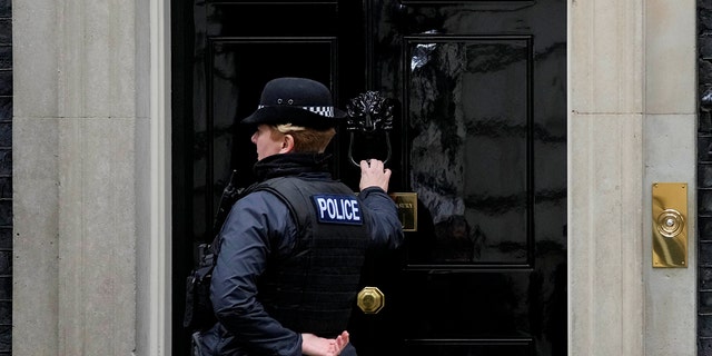 A police officer knocks on the door to 10 Downing Street in London, Tuesday, Jan. 11, 2022. Police are in contact with the Cabinet Office over claims the prime minister's aide organized a "bring your own booze" Downing Street party in May 2020 during the first virus lockdown.