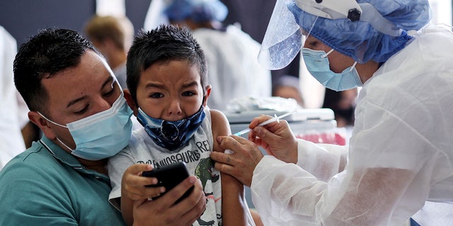 보고타의 예방접종 센터에서 의료진이 신종 코로나바이러스 COVID-19에 대해 중국 회사 Sinovac에서 개발한 CoronaVac 백신을 소년에게 접종하고 있습니다.  (사진: Leonardo Munoz/AFP) (Getty Images를 통한 Leonardo Munoz/AFP의 사진)