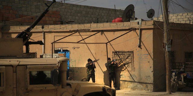 Kurdish-led Syrian Democratic Forces fighters, take their positions at an alley near Gweiran Prison, in Hassakeh, northeast Syria, Sunday, Jan. 23, 2022. (AP Photo/Hogir Al Abdo)