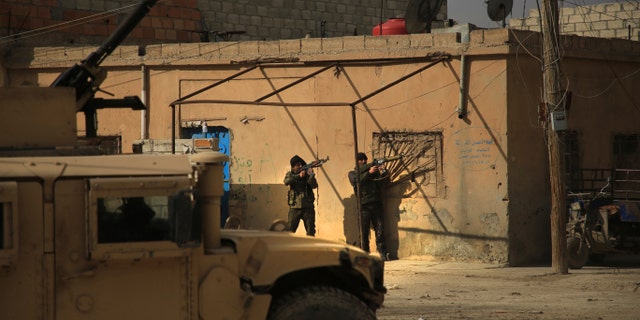 Kurdish-led Syrian Democratic Forces fighters, take their positions at an alley near Gweiran Prison, in Hassakeh, northeast Syria, Sunday, Jan. 23, 2022. (AP Photo/Hogir Al Abdo)