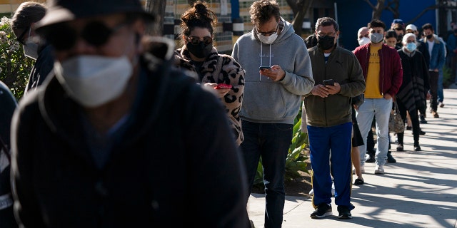 People wait in line for a COVID-19 test in Los Angeles, Jan. 4, 2022. Scientists are seeing signals that COVID-19′s alarming omicron wave may have peaked in Britain and is about to do the same in the U.S., at which point cases may start dropping off dramatically. 