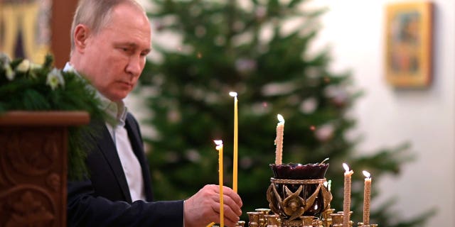 Le président russe Vladimir Poutine allume une bougie pendant la liturgie orthodoxe de Noël à Novo-Ogaryovo, près de Moscou, Russie, le jeudi 6 janvier 2022. (Alexei Nikolsky / Spoutnik, photo de la piscine du Kremlin via AP)