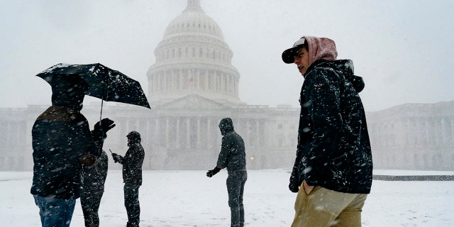 Visitors from France enjoy the scenery as a winter storm delivers heavy snow to the Capitol in Washington, Monday, Jan. 3, 2022.