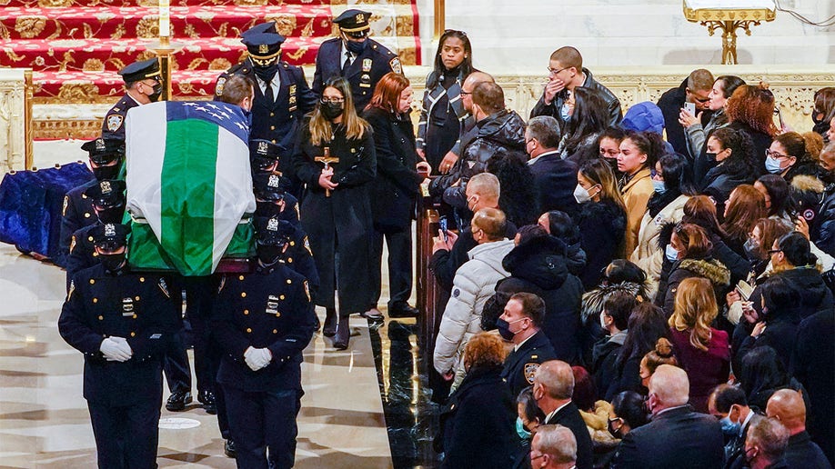 Dominique Rivera, wife of New York City Police Department (NYPD) officer Jason Rivera, walks behind her husband's casket holding a cross after his funeral mass at St. Patrick's Cathedral in the Manhattan borough of New York City, Jan. 28, 2022. 