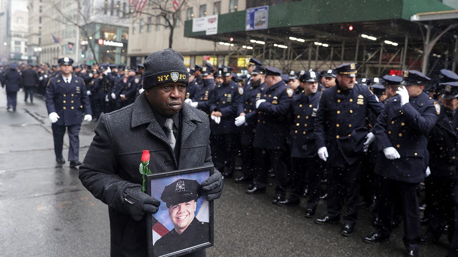 Calvin Hunt of Harlem holds a picture of New York City Police Department (NYPD) officer Jason Rivera, who was killed in the line of duty