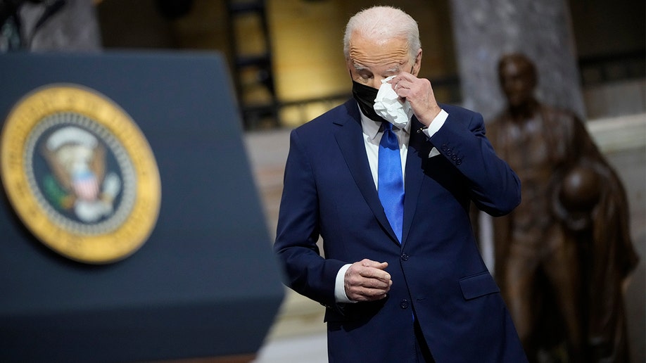 President Biden wipes his eyes as Vice President Kamala Harris speaks from Statuary Hall at the U.S. Capitol to mark one year since the Jan. 6 riot at the Capitol by supporters loyal to then-President Trump, Thursday, Jan. 6, 2022, in Washington. 