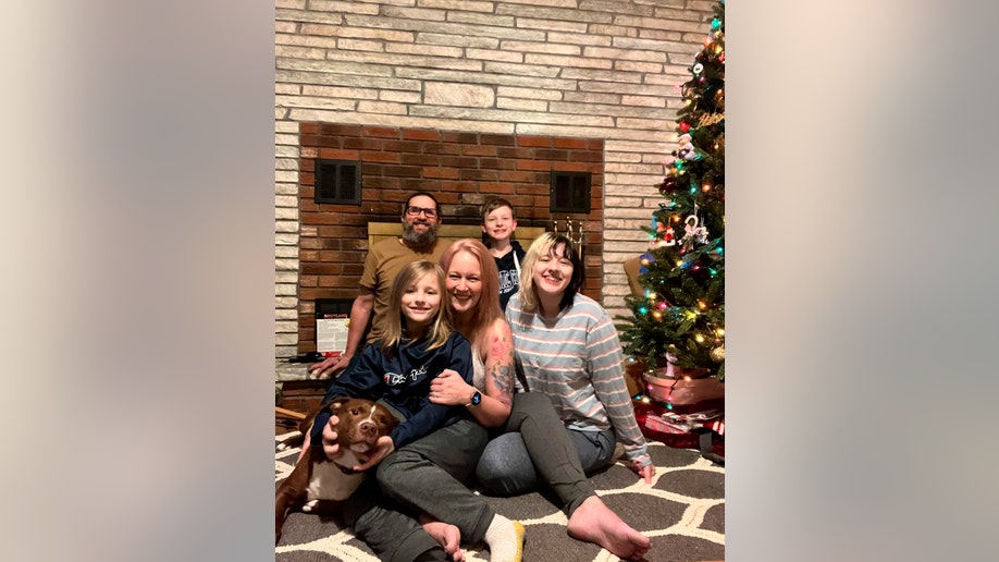 Rebekah Hogan, center, shows her with her family next to their Christmas tree at their home in Latham, N.Y. More than a year after a bout with COVID-19