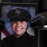 A New York Police officer holds a photo of Officer Jason Rivera while gathering for Rivera's funeral service, Friday, Jan. 28, 2022, outside St. Patrick's Cathedral in New York. (AP Photo/Yuki Iwamura)