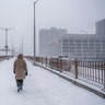 A woman walks towards the Brooklyn Bridge near City Hall during a snow storm on Saturday, Jan. 29, 2022, in New York.