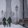 People walk down the Brooklyn Bridge during a snow storm on Saturday, Jan. 29, 2022, in New York.