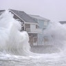 Waves crash over oceanfront homes during a noreaster in Scituate, Massachusetts on January 29, 2022.