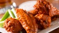 A plate of buffalo style chicken wings with celery and blue cheese with a beer on a bar or restaurant table.  Please see my portfolio for other food and drink images.