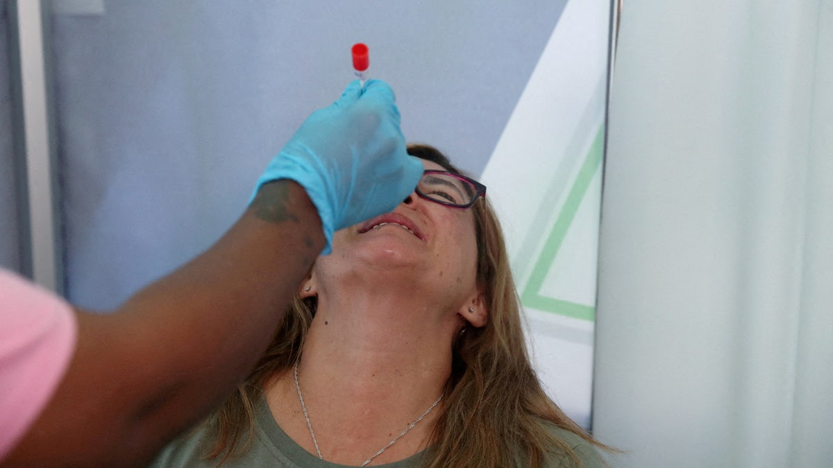 A healthcare worker collects a swab for a PCR test against COVID-19.