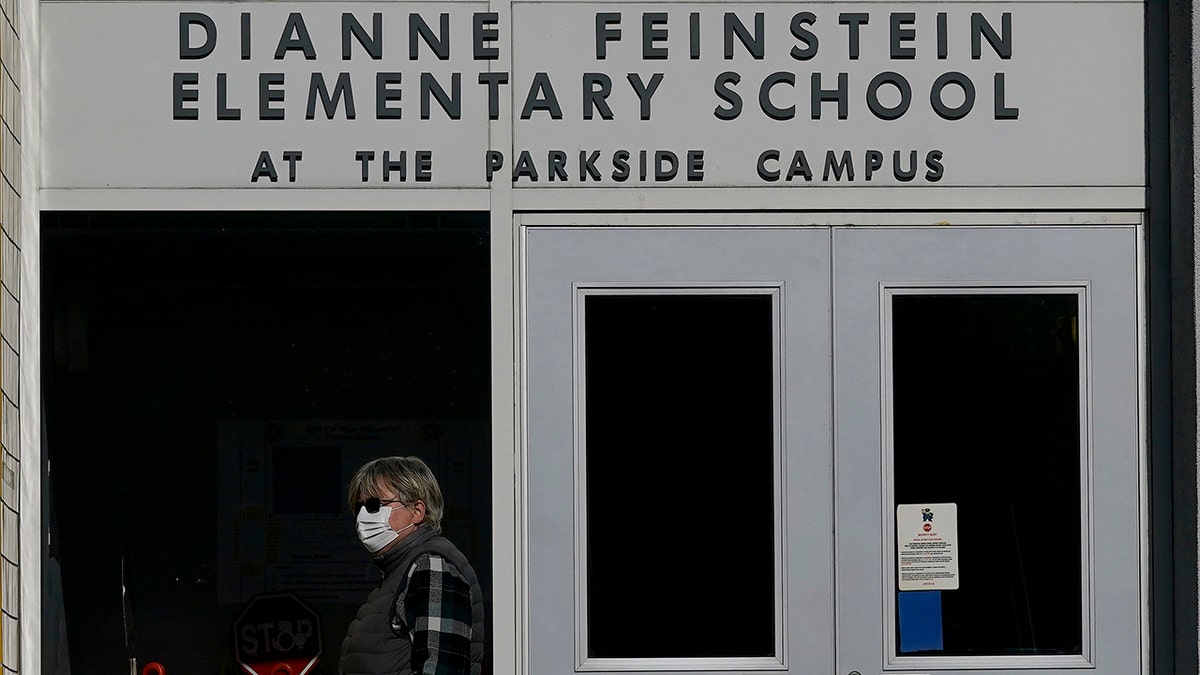 A pedestrian walks below a sign for Dianne Feinstein Elementary School in San Francisco on Dec. 17, 2020. 