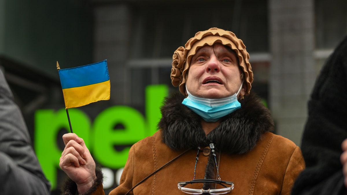 A woman becomes emotional while waving a Ukrainian flag at a Stand With Ukraine Rally in Times Square on February 24, 2022 in New York City. 