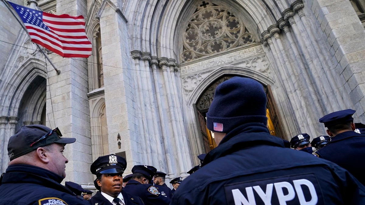 NYPD officers stand outside on Fifth Avenue before the casket of New York City Police Officer Wilbert Mora is delivered to St. Patrick's Cathedral for his wake, Tuesday, Feb. 1, 2022, in New York. Mora and Officer Jason Rivera were fatally wounded when a gunman ambushed them in an apartment as they responded to a family dispute.