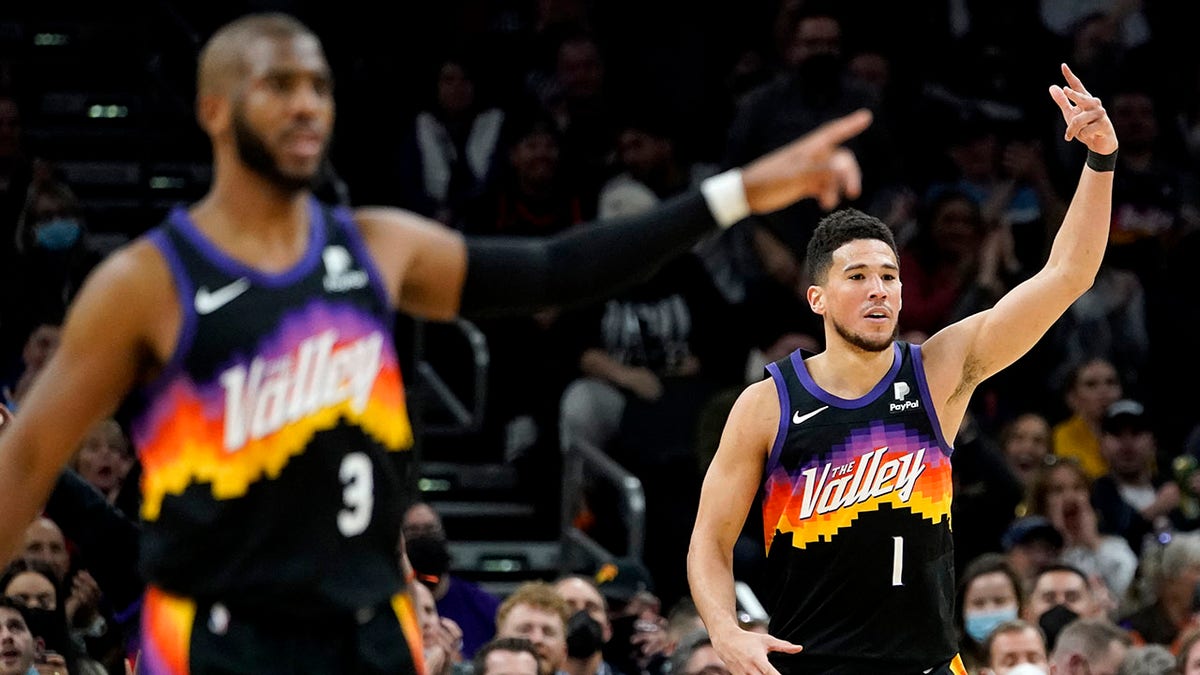 Phoenix Suns guard Devin Booker (1) and guard Chris Paul (3) motion after Booker made a three pointer against the Brooklyn Nets during the second half of an NBA basketball game, Tuesday, Feb. 1, 2022, in Phoenix.