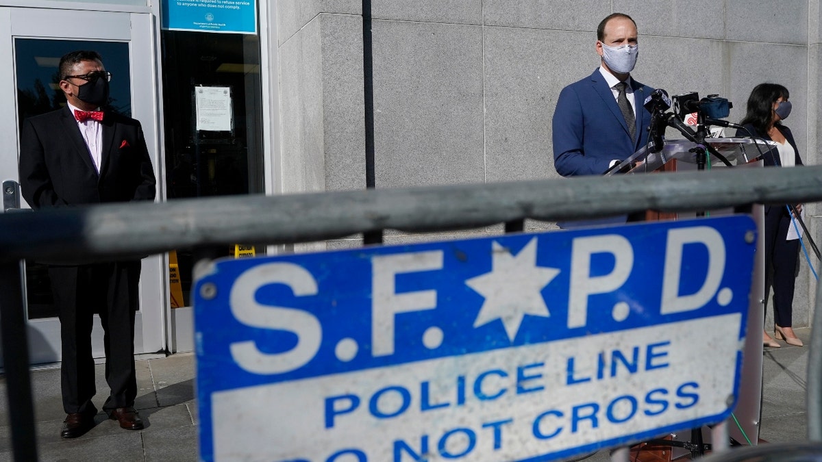 San Francisco District Attorney Chesa Boudin, foreground right, speaks between chief of staff David Campos, left, and assistant district attorney Rachel Marshall at a news conference in San Francisco, on Nov. 23, 2020. San Francisco's police chief is terminating an agreement allowing the DA's office to investigate police shootings and in-custody deaths, citing serious concerns over the office's impartiality. (AP Photo/Jeff Chiu, File)