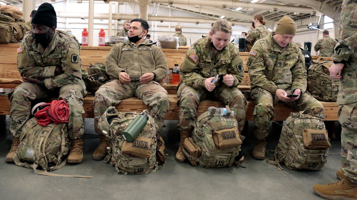 U.S. Army soldiers with the 18th Airborne Corps sit with their gear as they wait to board a plane for deployment to Europe Thursday, Feb. 3, 2022, from Fort Bragg, North Carolina.