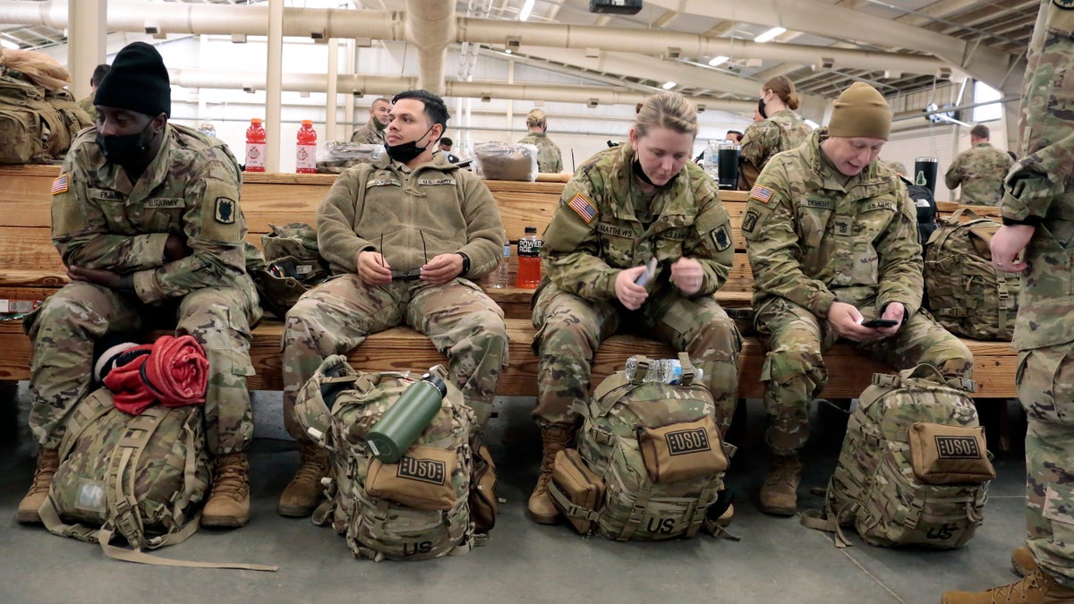 U.S. Army soldiers with the 18th Airborne Corps sit with their gear as they wait to board a plane for deployment to Europe Thursday, Feb. 3, 2022, from Fort Bragg, North Carolina.