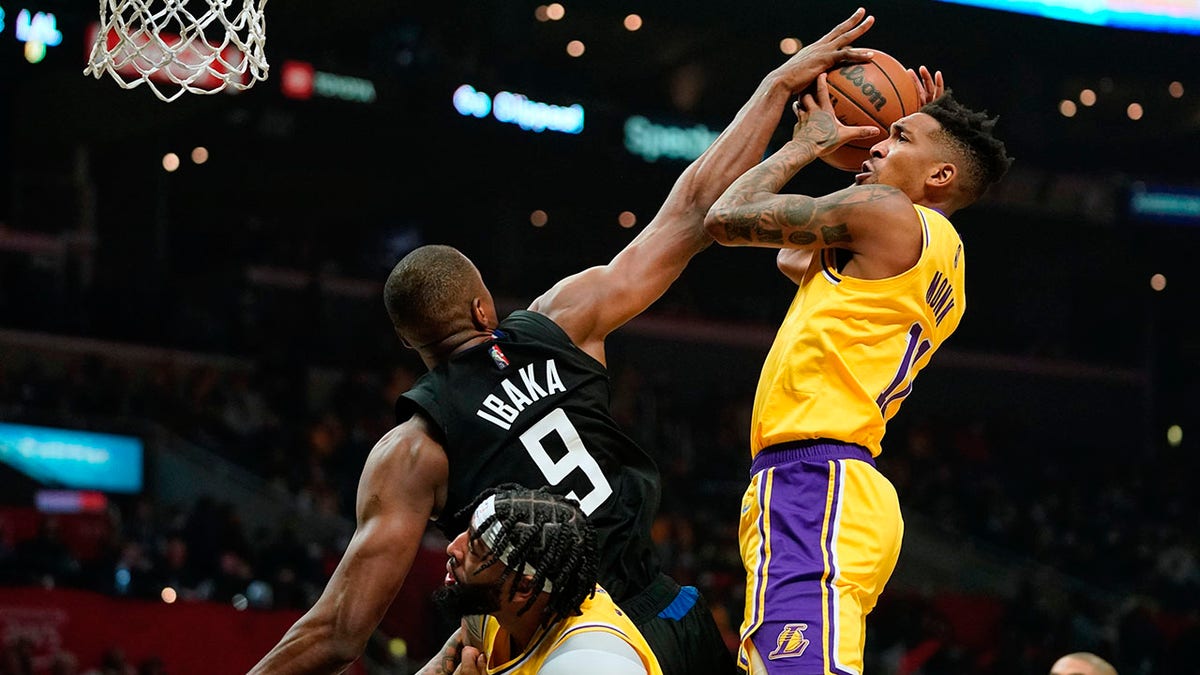 Los Angeles Lakers guard Malik Monk, right, shoots as Los Angeles Clippers center Serge Ibaka, left, defends while forward Anthony Davis stands by during the first half of an NBA basketball game Thursday, Feb. 3, 2022, in Los Angeles.