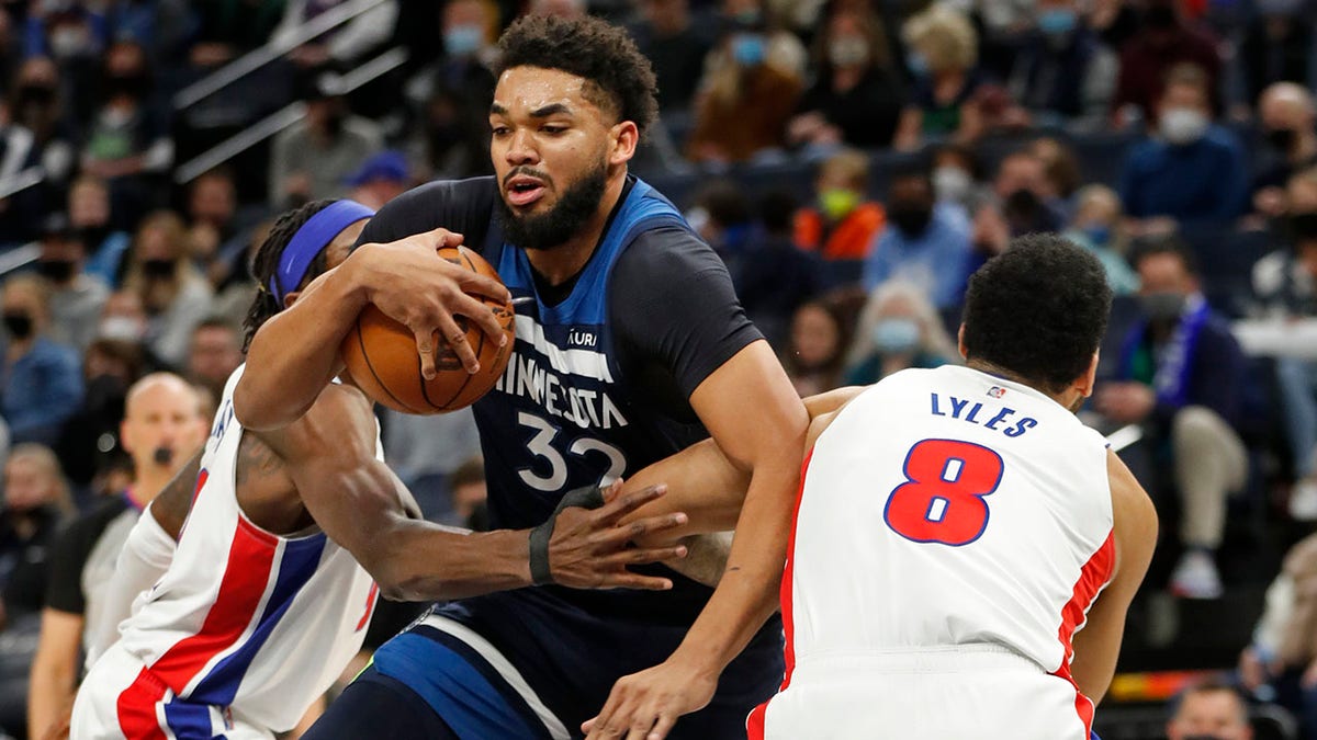 Minnesota Timberwolves center Karl-Anthony Towns (32) works between Detroit Pistons forward Jerami Grant, left, and Detroit Pistons center Trey Lyles, right, in the first quarter of an NBA basketball game, Sunday, Feb. 6, 2022, in Minneapolis.